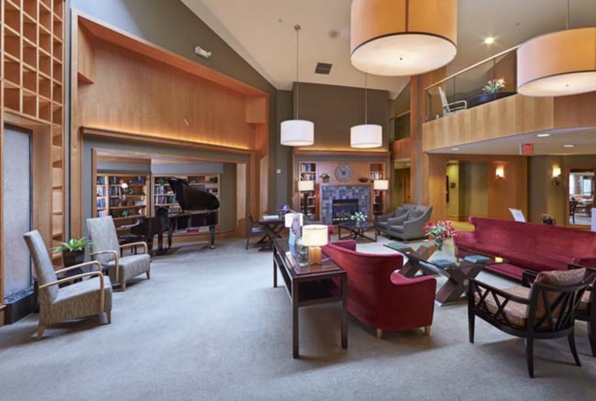 A spacious and modern living room with a piano and library area.