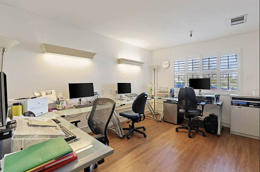 A modern office space featuring multiple workstations equipped with computers and ergonomic chairs.