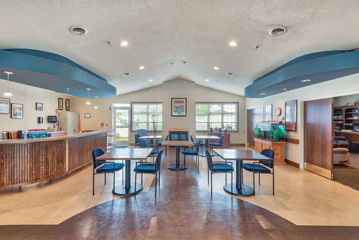 A modern dining area with blue accents, featuring tables and chairs under bright lighting.