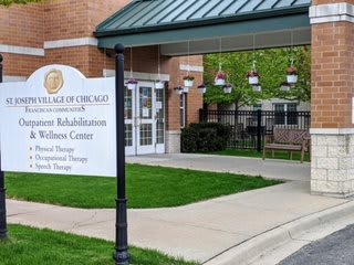 Entrance to a rehabilitation and wellness center with a sign and well-maintained landscaping.