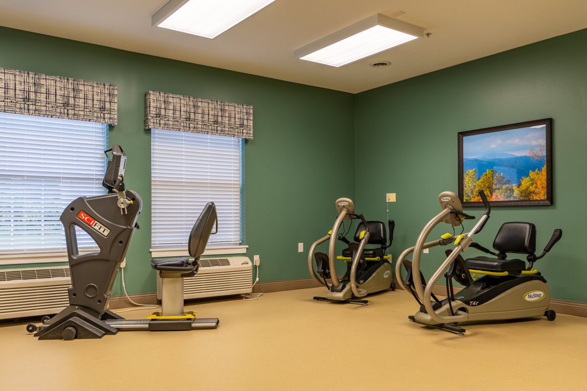 A small gym with exercise equipment and a green accent wall.