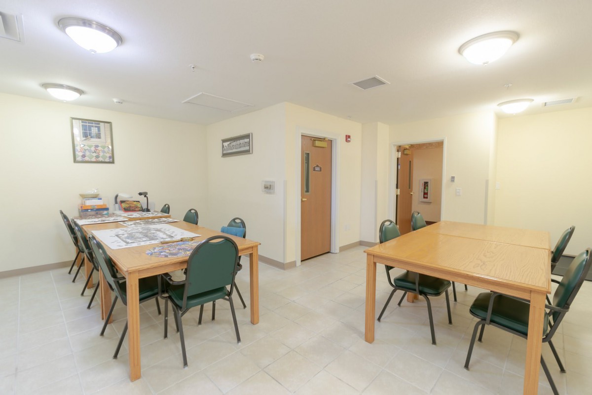 An empty meeting room with tables and chairs arranged neatly.