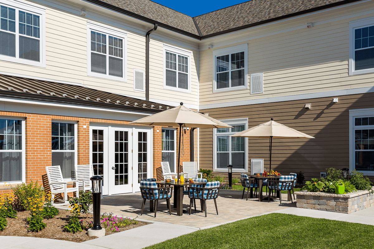 A cozy outdoor patio area with tables, chairs, and umbrellas in front of a building.