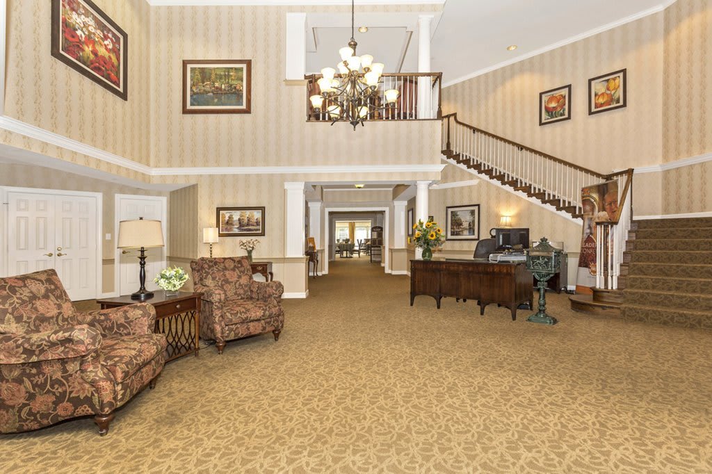 A spacious and elegant hotel lobby featuring a grand staircase, comfortable seating, and a chandelier.