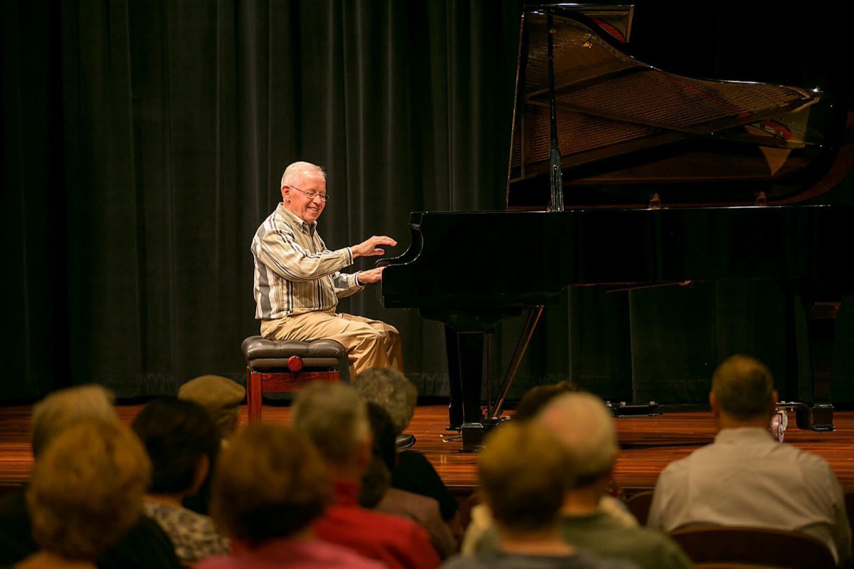 A pianist performing on stage in front of an audience.
