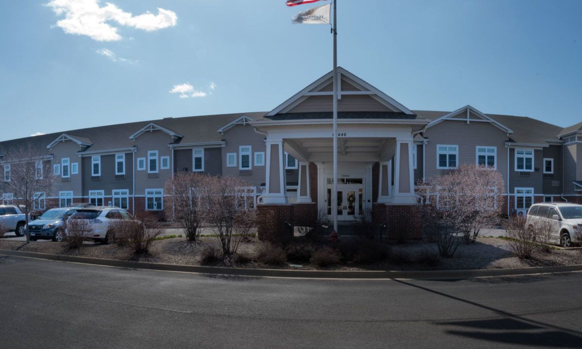 A two-story building with a prominent entrance and flagpole under a bright sky.