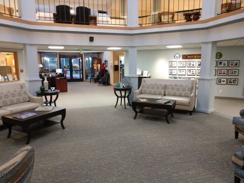 A spacious lobby area with sofas and tables, featuring a carpeted floor and visible reception desk.