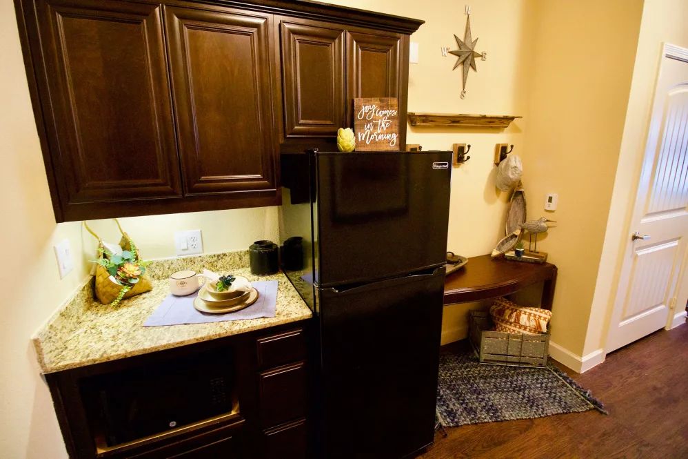 A cozy kitchen corner with dark wooden cabinets and a compact refrigerator.