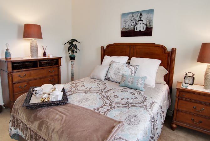 A cozy bedroom with a neatly made bed, decorative pillows, and a warm ambiance.