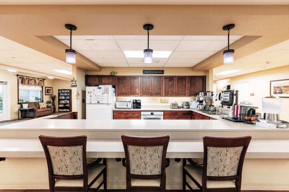 A modern kitchen interior with a large countertop and dining chairs.