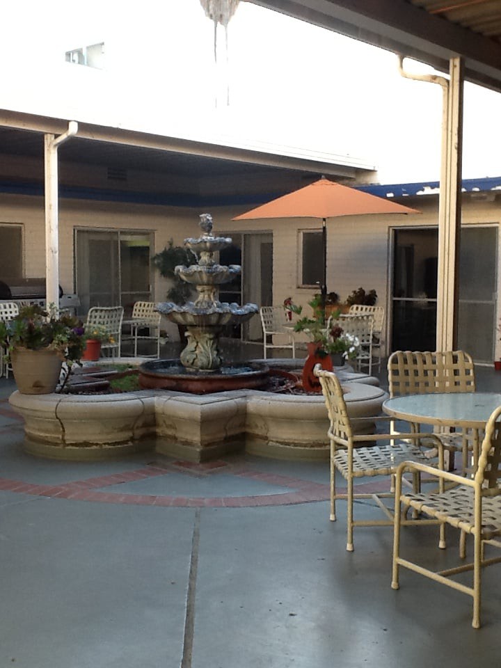 A tranquil courtyard featuring a fountain surrounded by outdoor seating and plants.