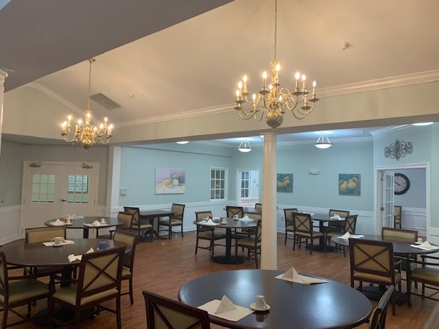 A cozy dining room with elegant chandeliers and neatly arranged tables and chairs.