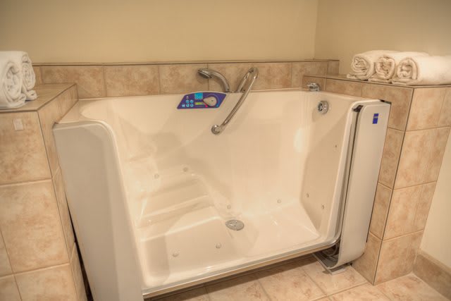 A walk-in bathtub designed for accessibility, featuring a secure door and tiled surroundings.