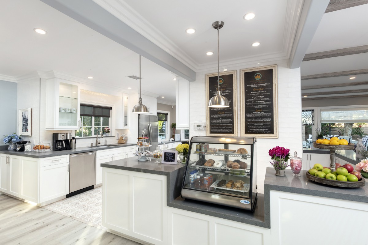 A modern kitchen with sleek design features, including a central island with a glass display case and overhead pendant lighting.