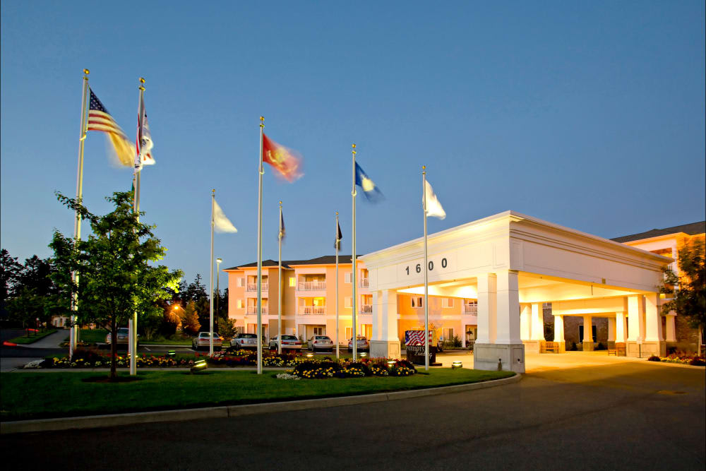 A hotel building with multiple flags displayed outside during the evening.