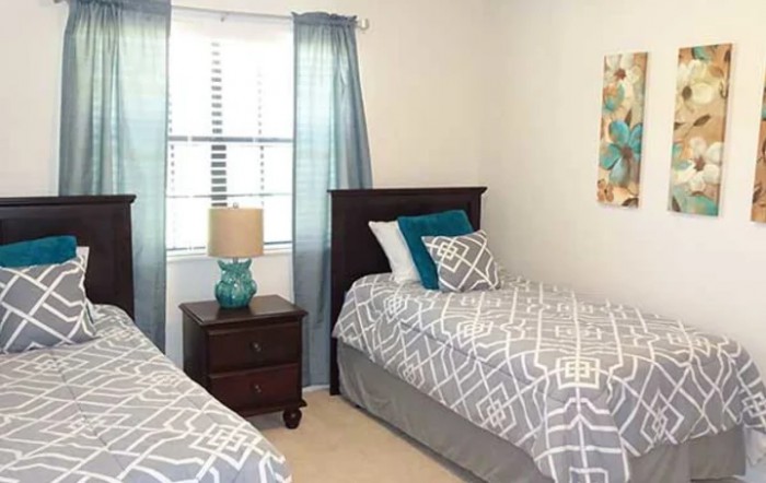 A cozy bedroom featuring twin beds with patterned bedding and a bedside table with a lamp.