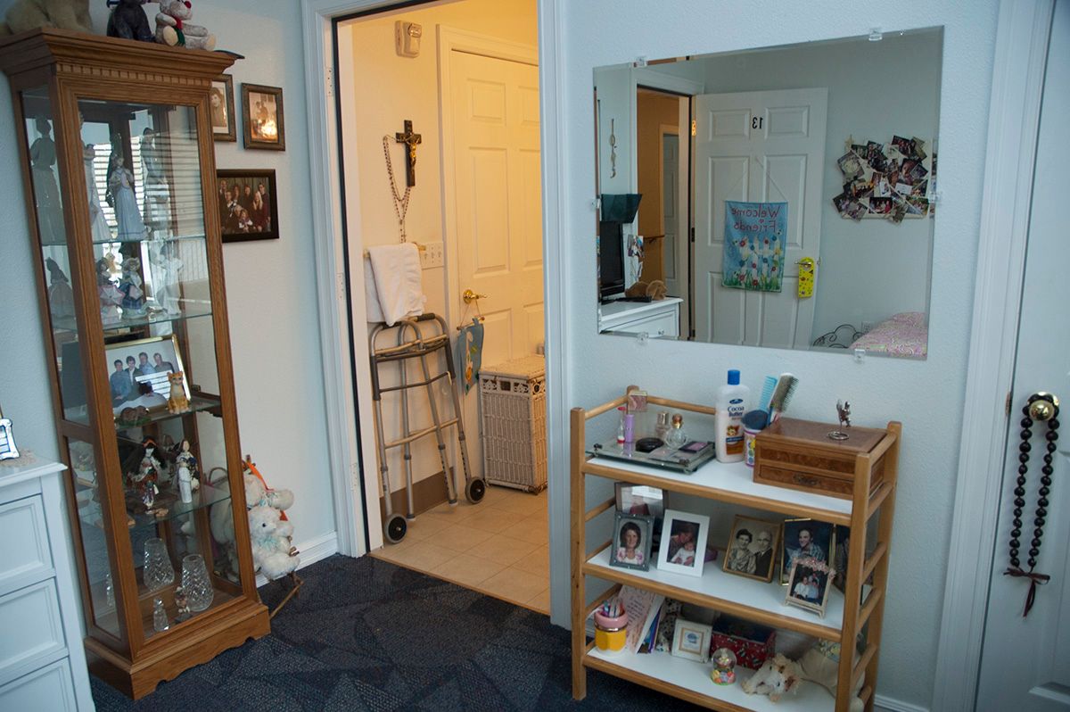 A cozy living space with shelves, a mirror, and a walker nearby.