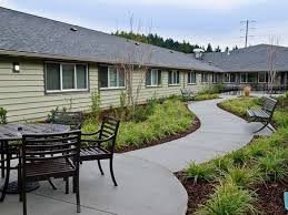 Outdoor seating area along a landscaped pathway in front of a residential building.