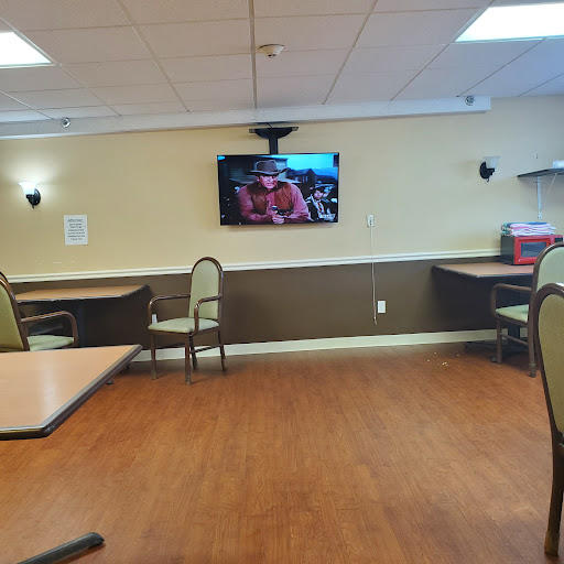 An empty dining area featuring tables and chairs, with a television mounted on the wall.