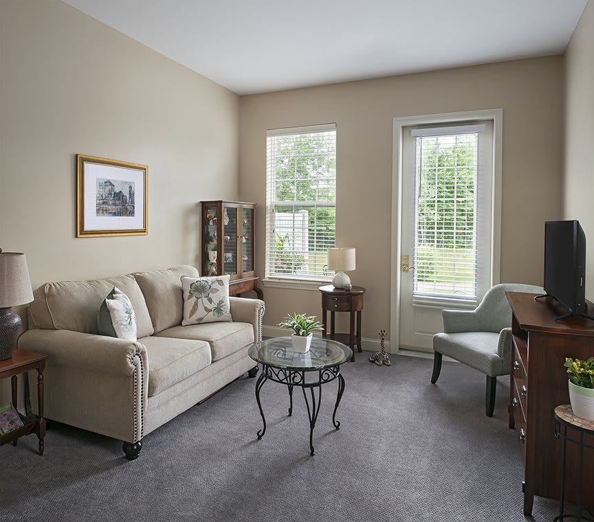 A cozy living room with a sofa, armchair, and glass coffee table.