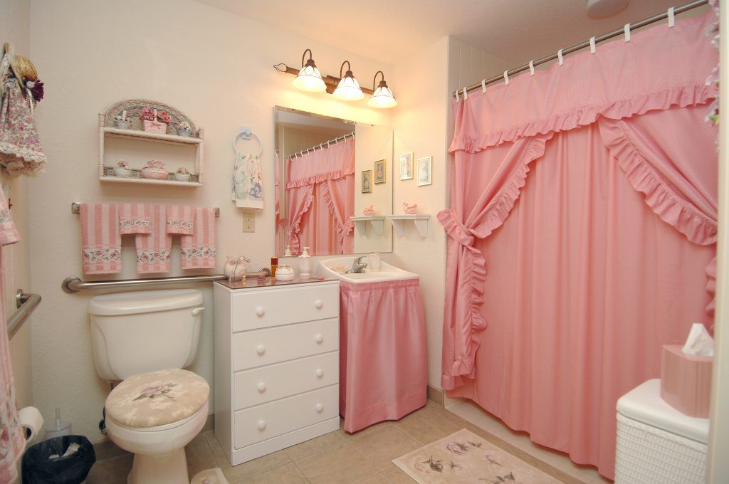 A cozy bathroom decorated with pink accents and a matching shower curtain, creating a warm and inviting atmosphere.