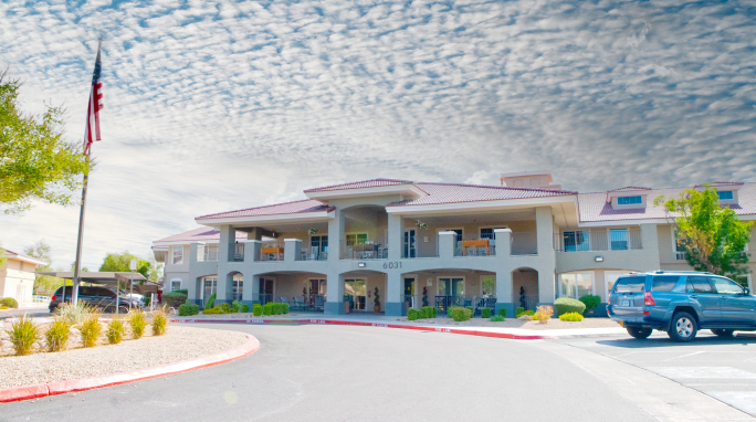 A two-story building with a cloudy sky backdrop and landscaped surroundings.