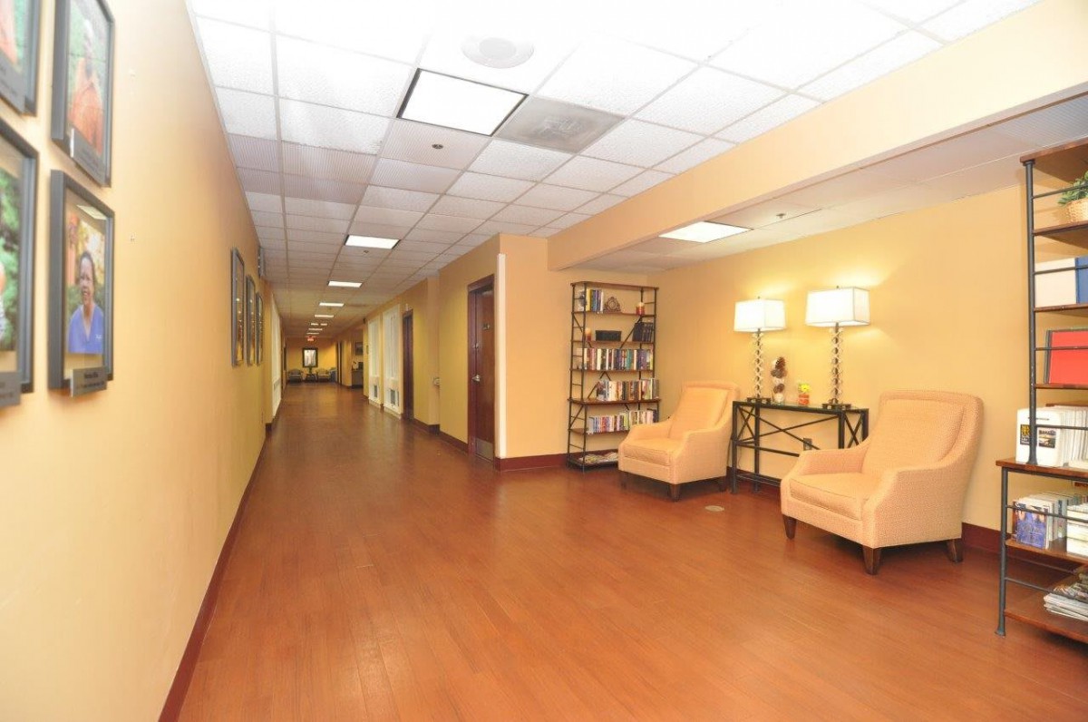 A well-lit hallway with wooden floors, yellow walls, and comfortable furniture.
