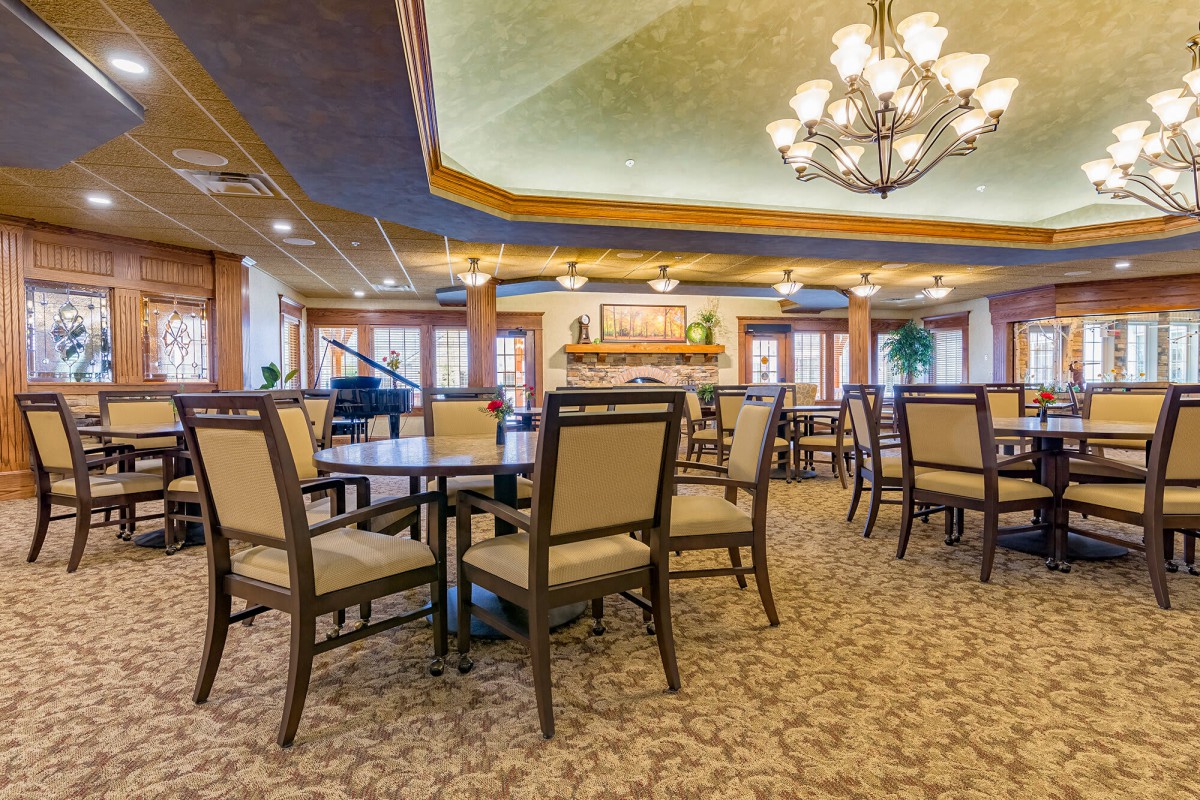 An elegant dining room with multiple tables and chairs, adorned with a chandelier.