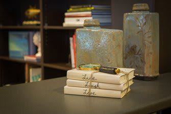 A neatly stacked set of books with decorative ceramic pieces in a cozy interior setting.