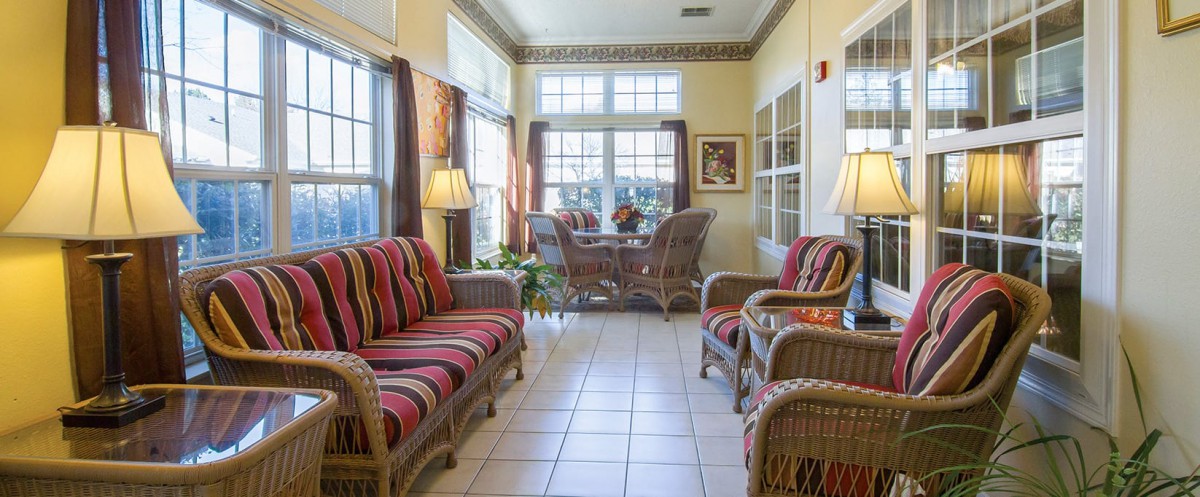 A cozy living room with wicker furniture and ample natural light streaming through large windows.