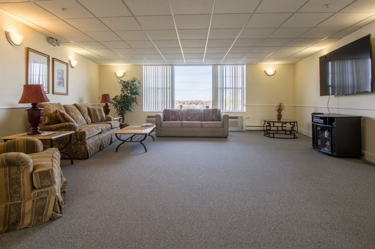 A spacious living room with sofas, a coffee table, and large windows.