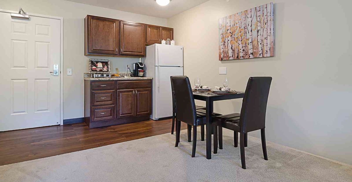 Compact kitchen and dining area with wooden cabinets and a small dining table.