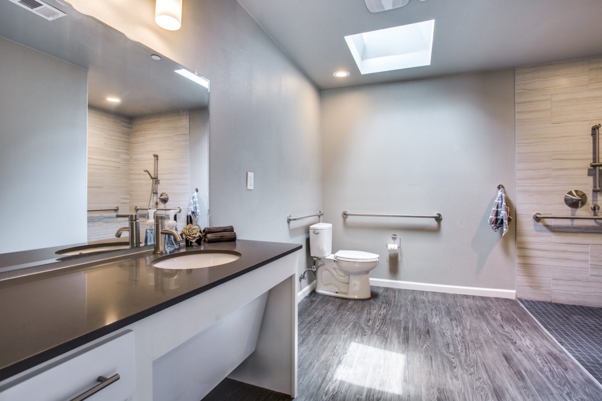 A modern bathroom with sleek gray walls, a skylight, and stylish fixtures.