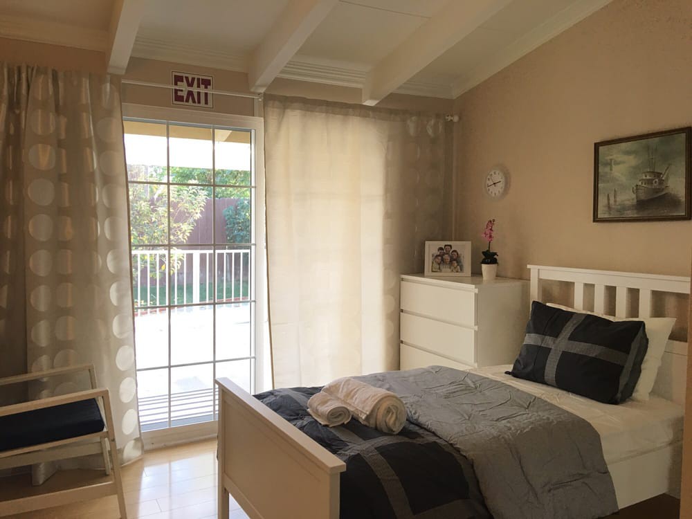 A cozy, well-lit bedroom with minimalist decor and neutral tones.
