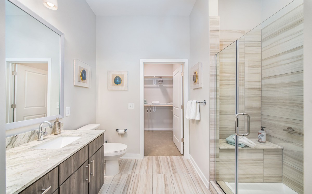A modern and bright bathroom with a glass shower, vanity, and toilet.