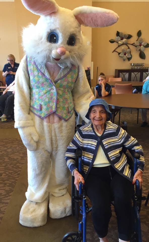 An elderly person in a wheelchair poses with someone in a bunny costume.