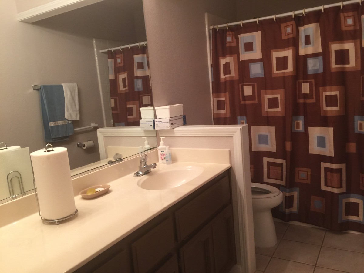 A bathroom featuring a sink and mirror, with a colorful shower curtain in the background.