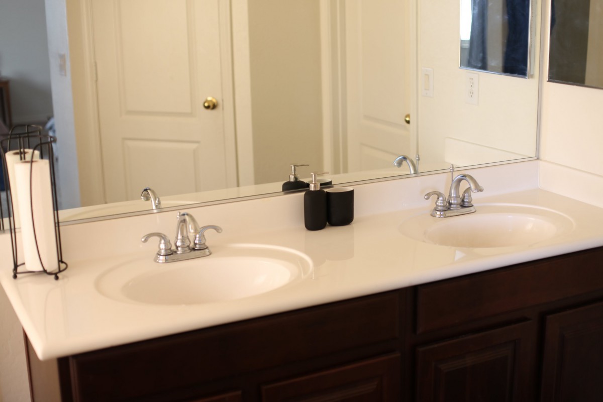 A bathroom with a countertop featuring double sinks and a large mirror.