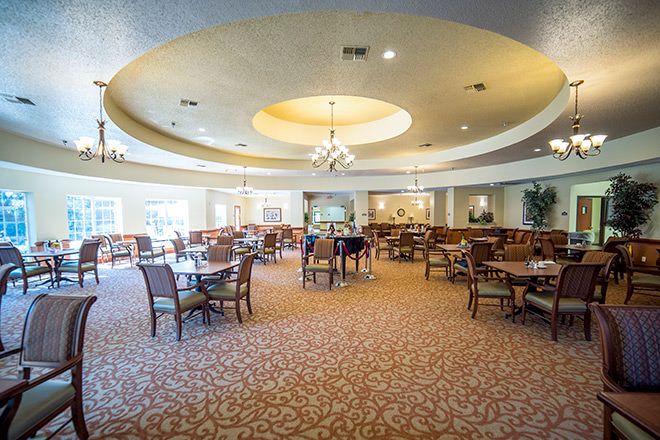A spacious and elegantly designed dining area with multiple tables and chairs, featuring a decorative chandelier.