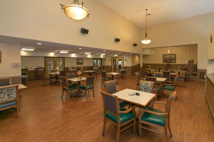 A spacious dining area with neatly arranged tables and chairs, featuring warm lighting and a comfortable ambiance.