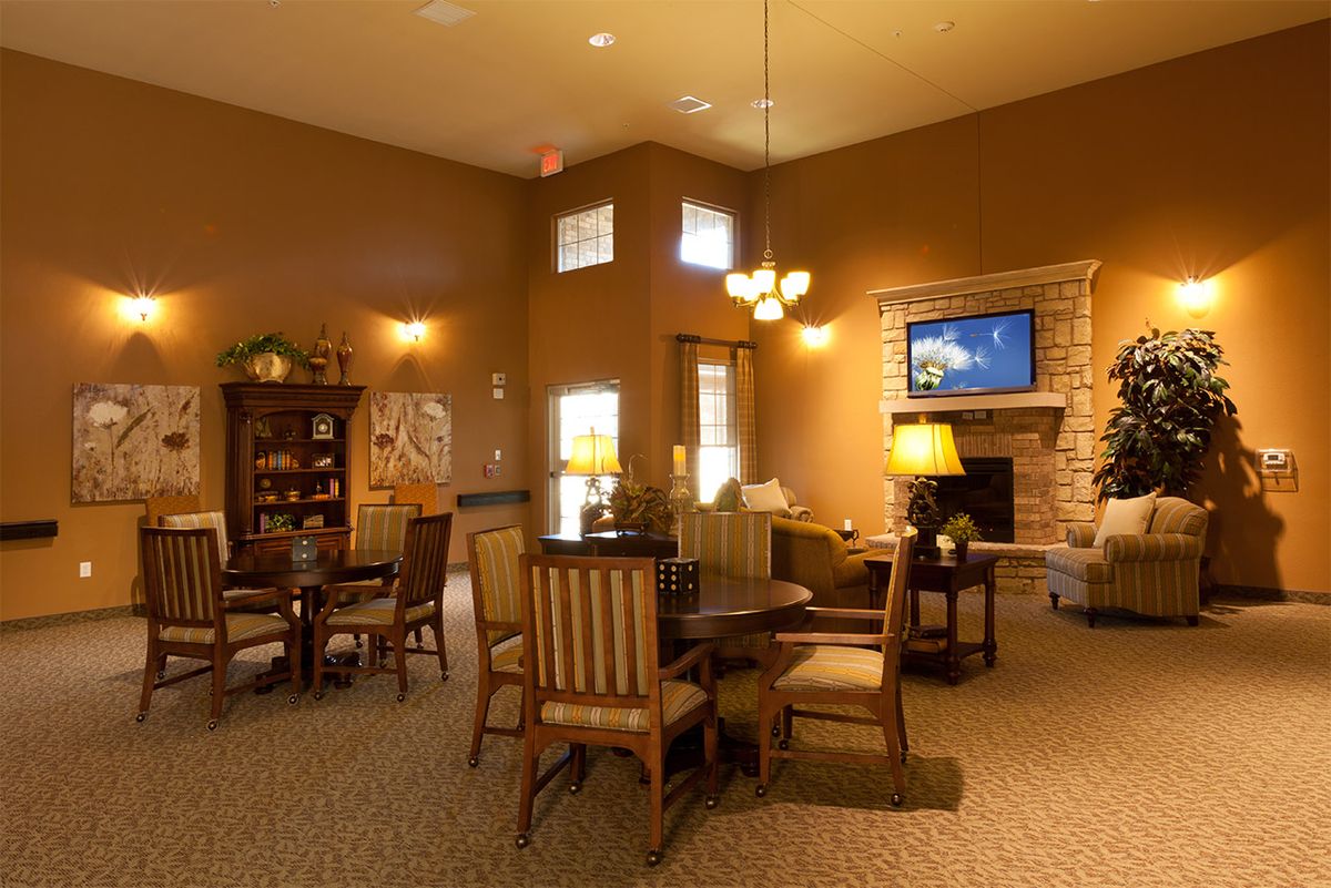 A cozy living room with warm lighting, featuring wooden furniture and a television near the fireplace.