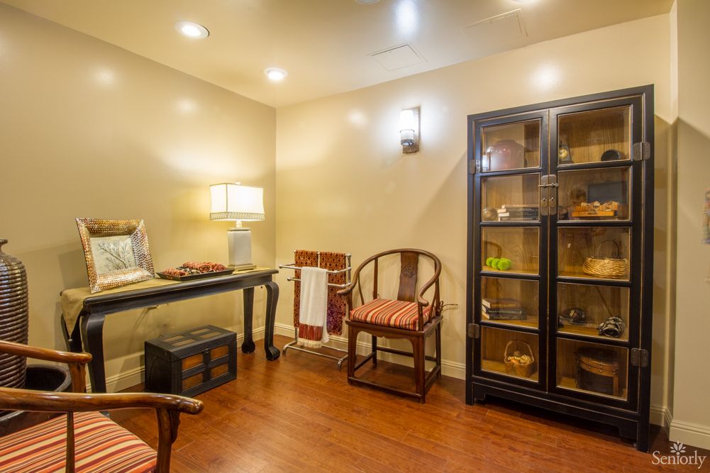 Cozy room interior with warm lighting, featuring chairs and a display cabinet.