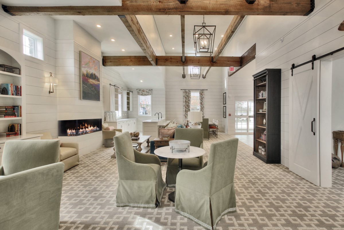 A spacious and modern living room featuring a beamed ceiling, fireplace, and neutral-colored furniture arranged in an open layout.