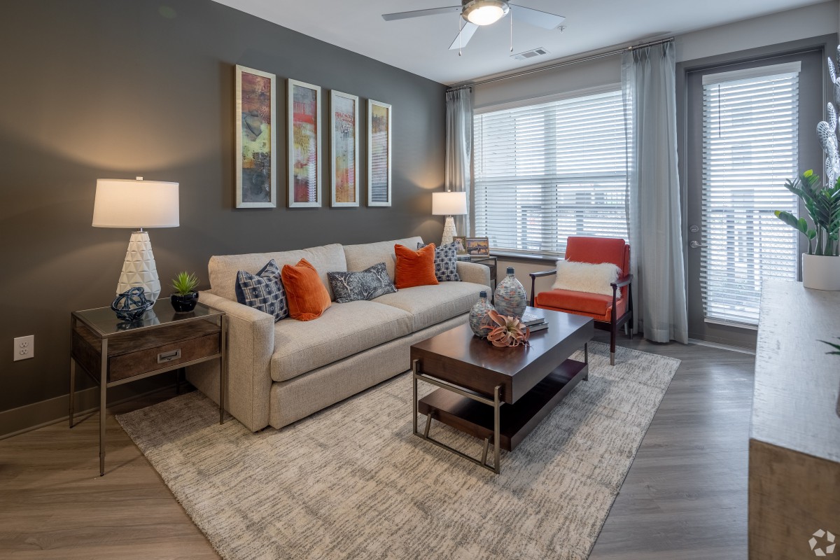 A modern living room with a cozy arrangement featuring a beige couch, colorful pillows, and wall art.