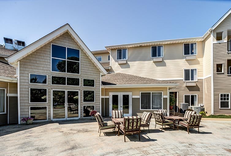 A spacious residential house with large windows and a patio featuring outdoor seating.