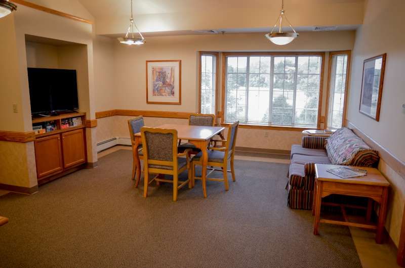 A spacious living room with a dining area, featuring a table, chairs, sofa, and TV.