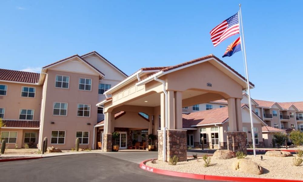 The front entrance of a multi-story building with flags flying overhead.
