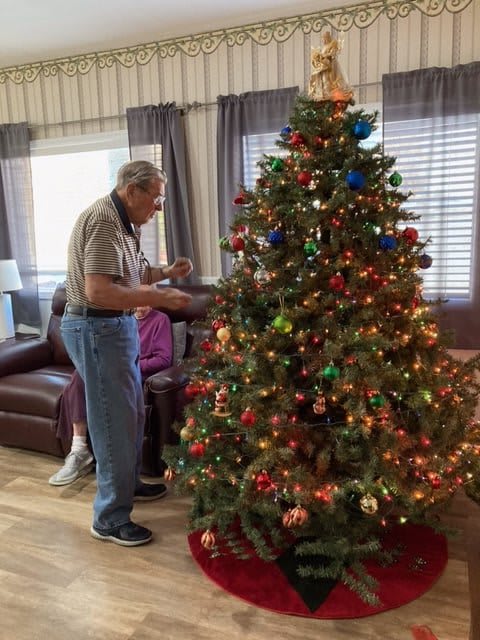 A person decorating a Christmas tree in a cozy living room.