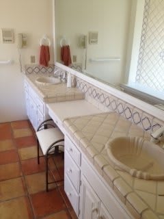 A bathroom featuring a double sink with tiled countertops and a large mirror.