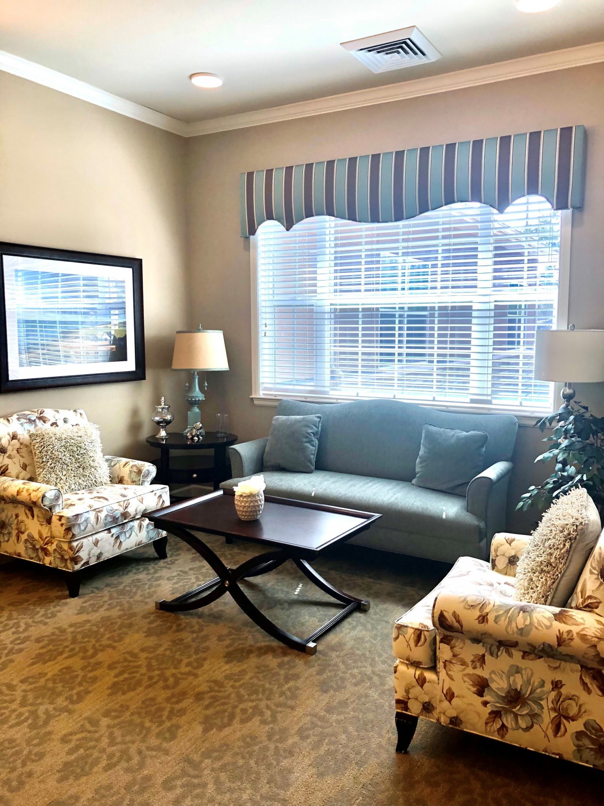 A cozy living room with a sofa, armchairs, and a coffee table near a large window.
